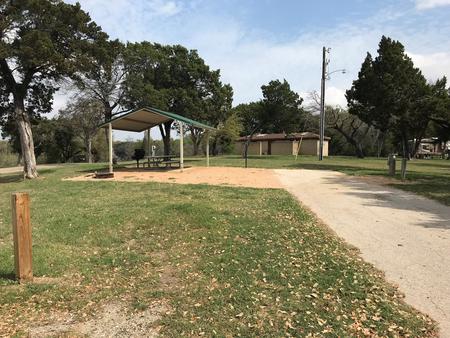 RV site with grill, fire ring, covered picnic table, and restroom/shower facilities nearby
