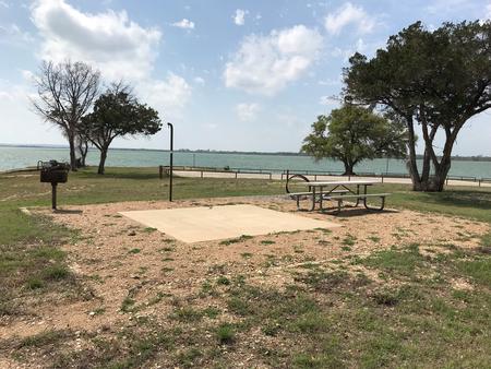 Tent site with picnic table, grill, fire ring, and Waco Lake in the background