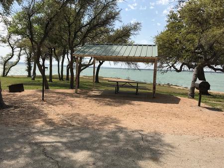 Covered picnic table, grill, fire ring, and Waco Lake in the background