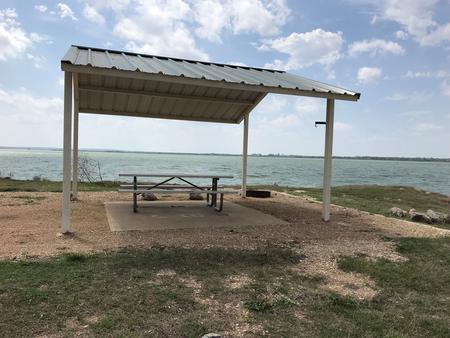 Tent site with covered picnic table and fire ring.  Site is located very close to shoreline of Waco Lake