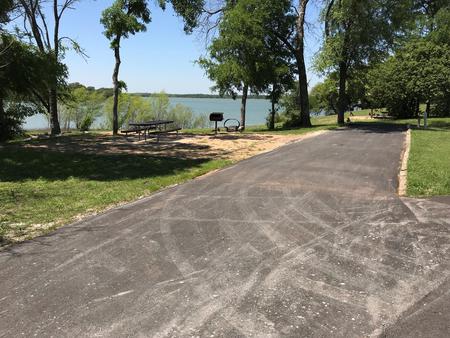 RV site with picnic table, grill, fire ring, and Waco Lake in the background
