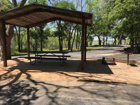 Covered picnic table, grill, and fire ring with Waco Lake in the background