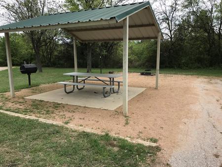 RV site with covered picnic table, grill, and fire ring