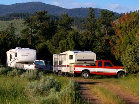Photo of a trucks and trailers in a campsite area.Arch Dam Campground
