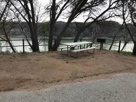 Picnic table and grill at site with Waco Lake in the background