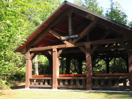 Large wooden pavilion, surrounded by trees and grass
