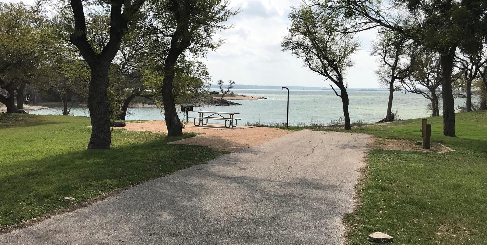 RV site with picnic table, grill, fire ring, and view of Waco Lake