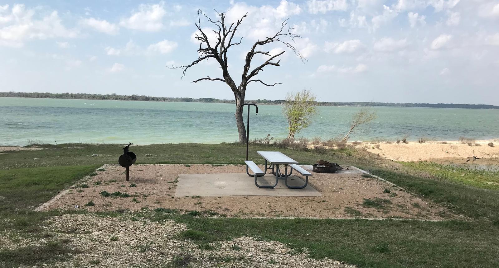 Tent site with picnic table, grill, and fire ring.  Site is located very close to shoreline of Waco Lake 
