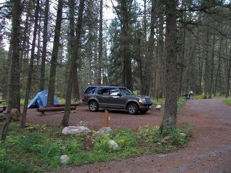Cabin Creek Campground - Campsite surrounded by pine trees,  picnic table, fire ring, vehicle & tentCampsite