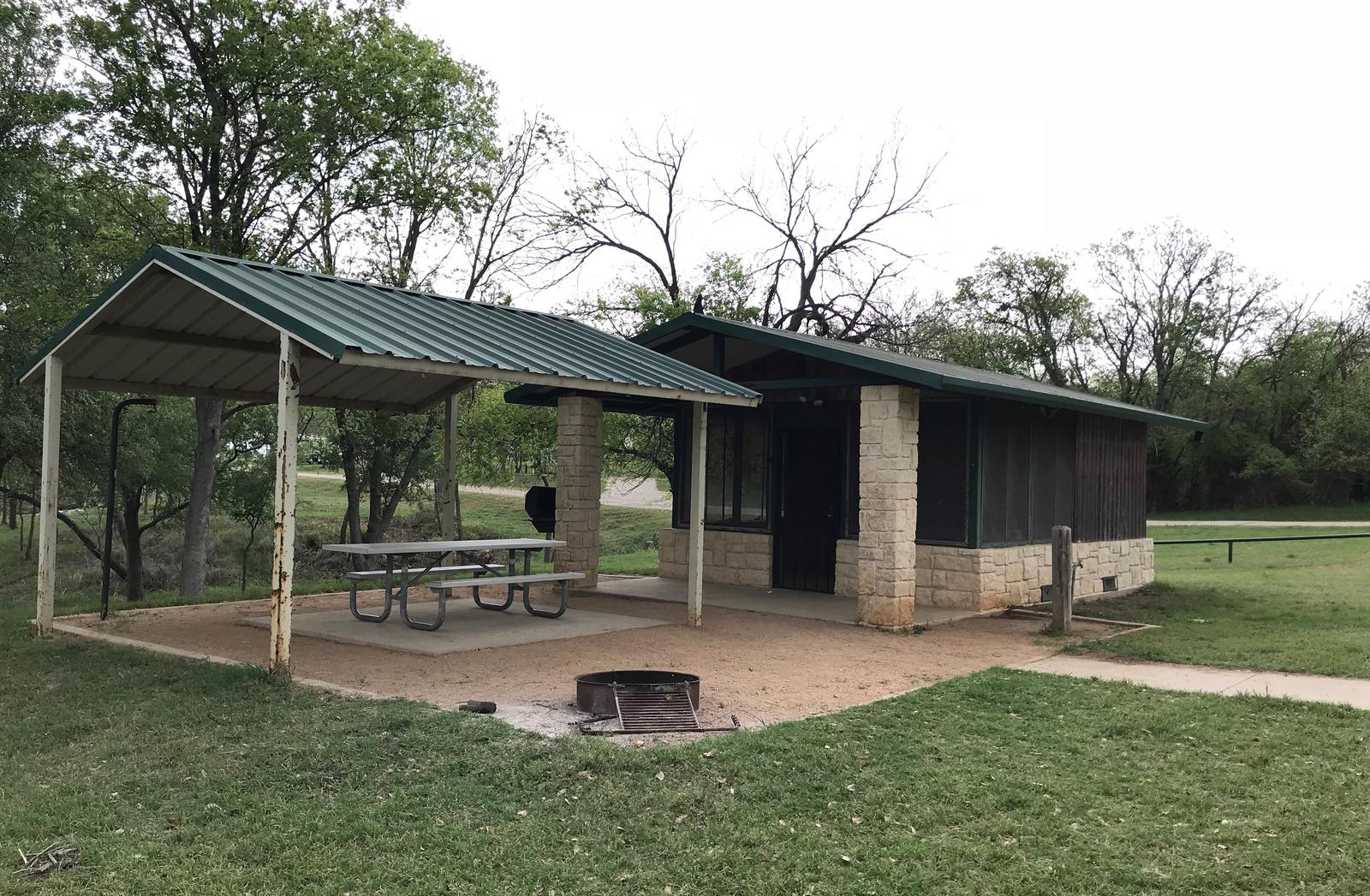 Screen shelter with covered picnic table, grill, and fire ring