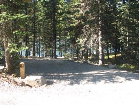 Site 18, campsite surrounded by pine trees, picnic table & fire ringSite 18