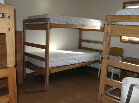 Three sets of twin wooden bunk beds with mattresses in a bedroomCalf Creek Cabin bunk room