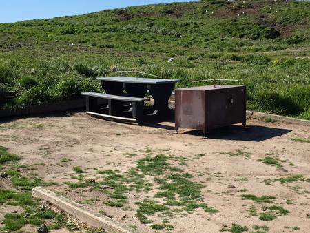 Picnic table and metal food storage box on terrace overlooking ocean, two buildings and lighthouse. ANACAPA ISLAND AREA - 002
