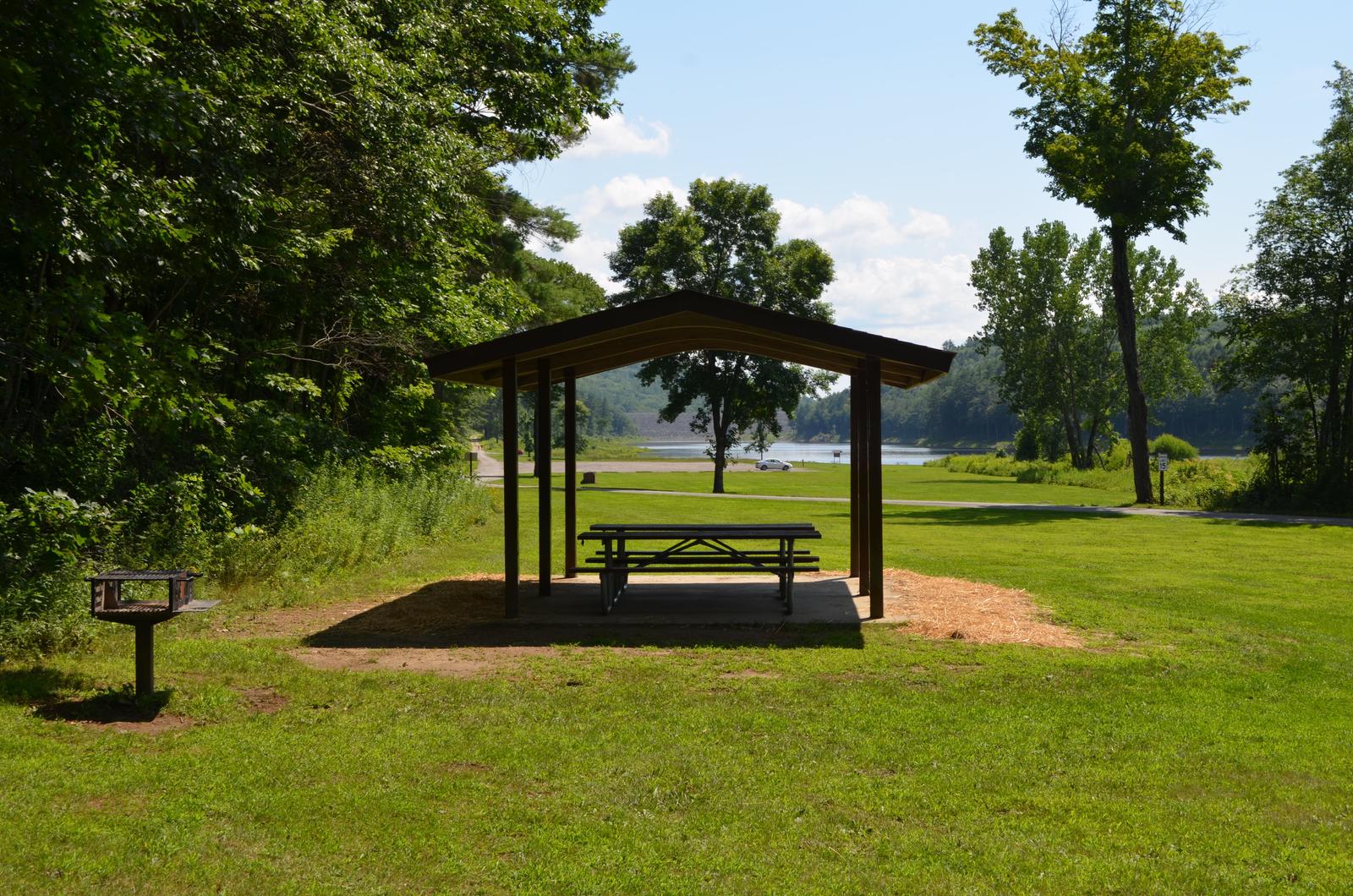 Alder shelter, with picnic tables and grill at Otter Brook Lake, with the lake in the background.Alder Shelter at Otter Brook Lake