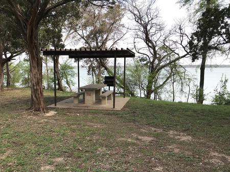 Covered table and grill at site with Waco Lake in the backgroundCovered picnic table and grill at site with Waco Lake in the background