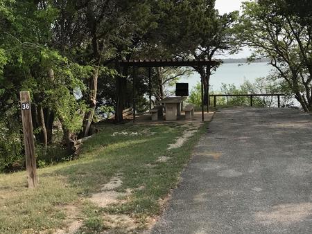 RV site with covered picnic table, grill, and Waco Lake in the background