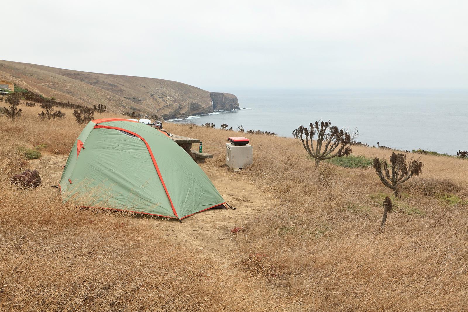 Tent sitting in dried grass on a ocean bluff overlooking the coastline.SANTA BARBARA ISLAND