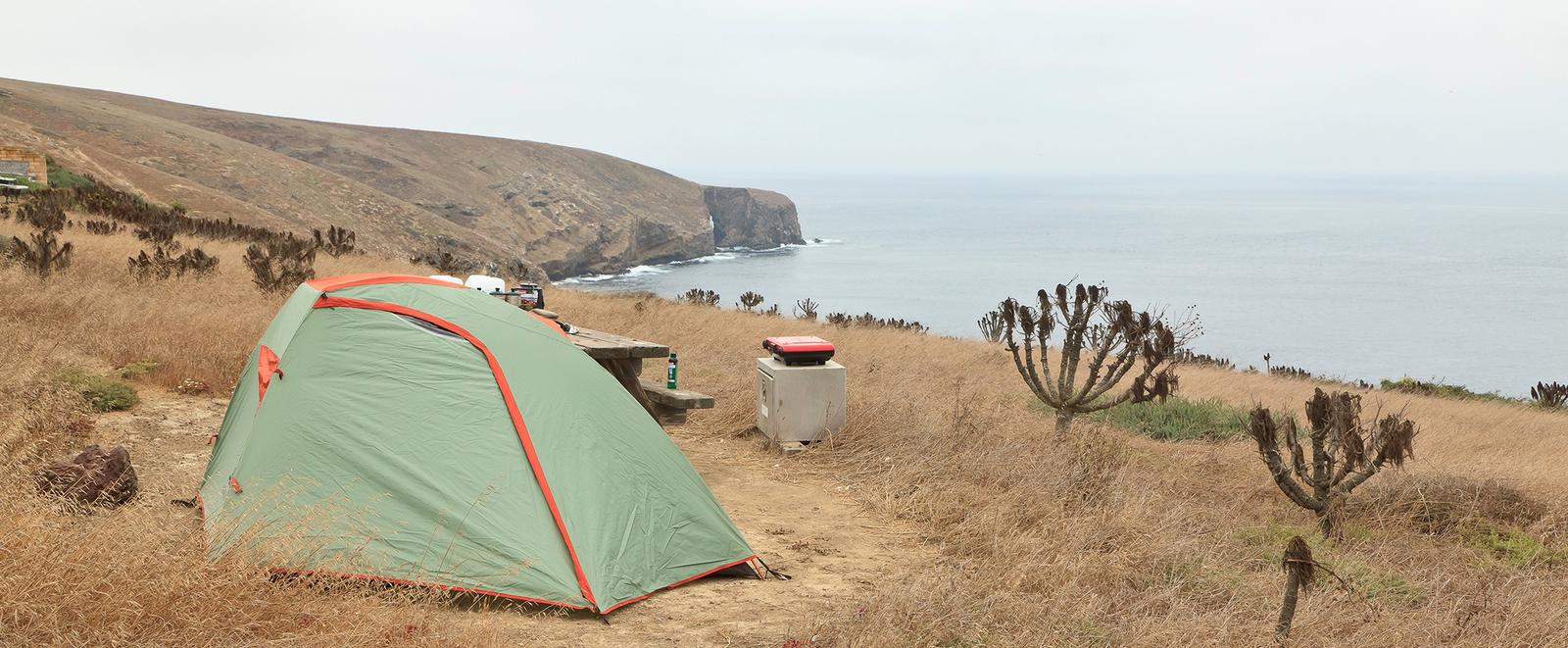 Tent sitting in dried grass on a ocean bluff overlooking the coastline.SANTA BARBARA ISLAND