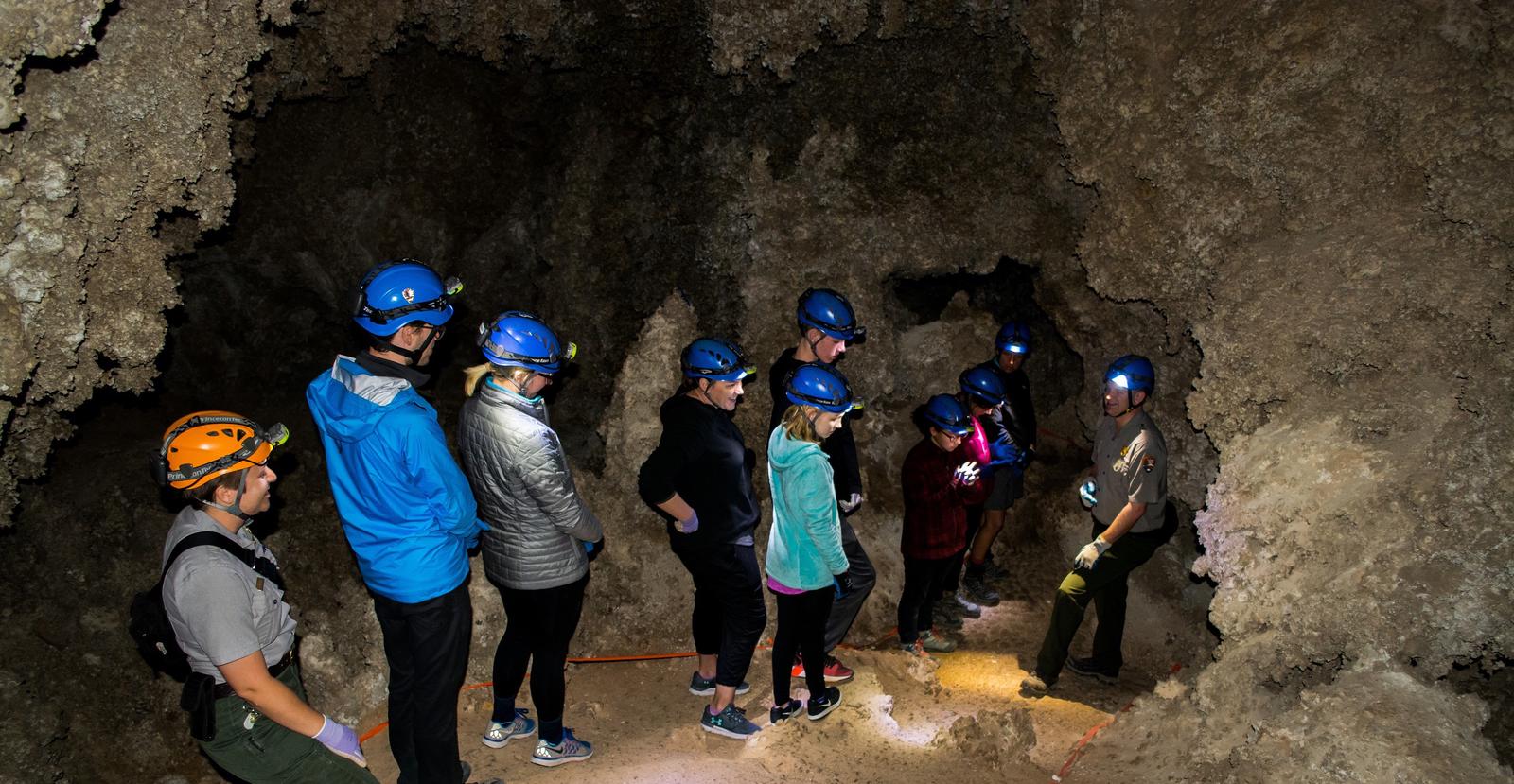 Photo of rangers and visitors in Lower Cave wearing caving helmets.