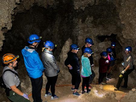 Photo of rangers and visitors in Lower Cave wearing caving helmets.Rangers and visitors in Lower Cave.