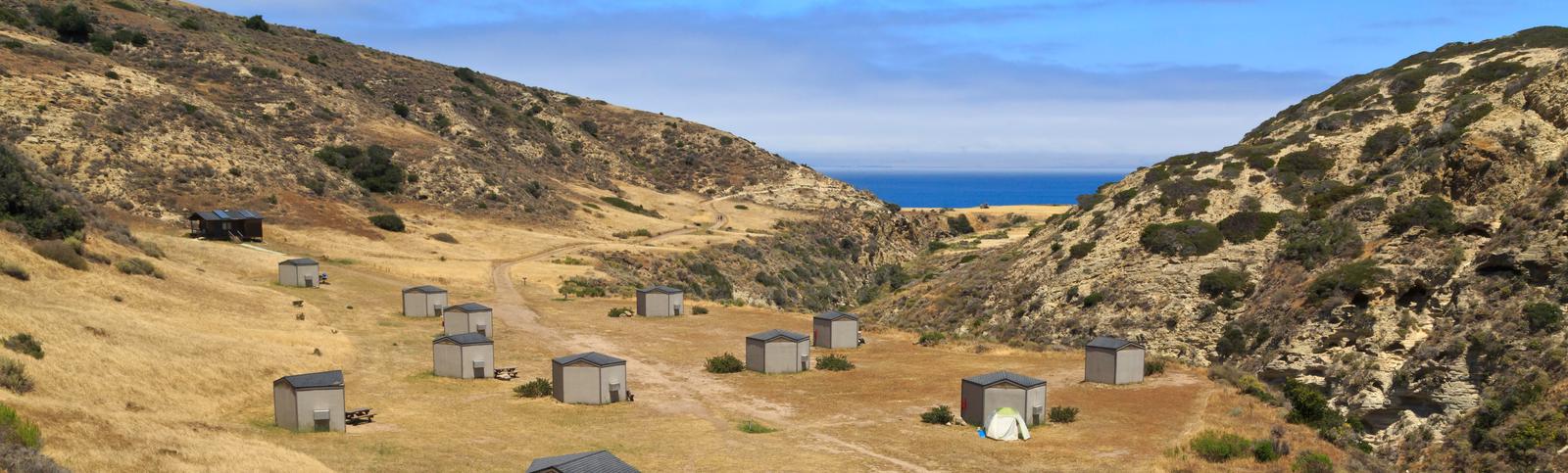 Eight foot tall wind shelters on a dry, grassy terrace overlooking the oceanSanta Rosa campground