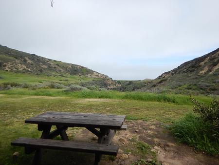 View of wide canyon with picnic table and green grass in foreground. Santa Rosa campground