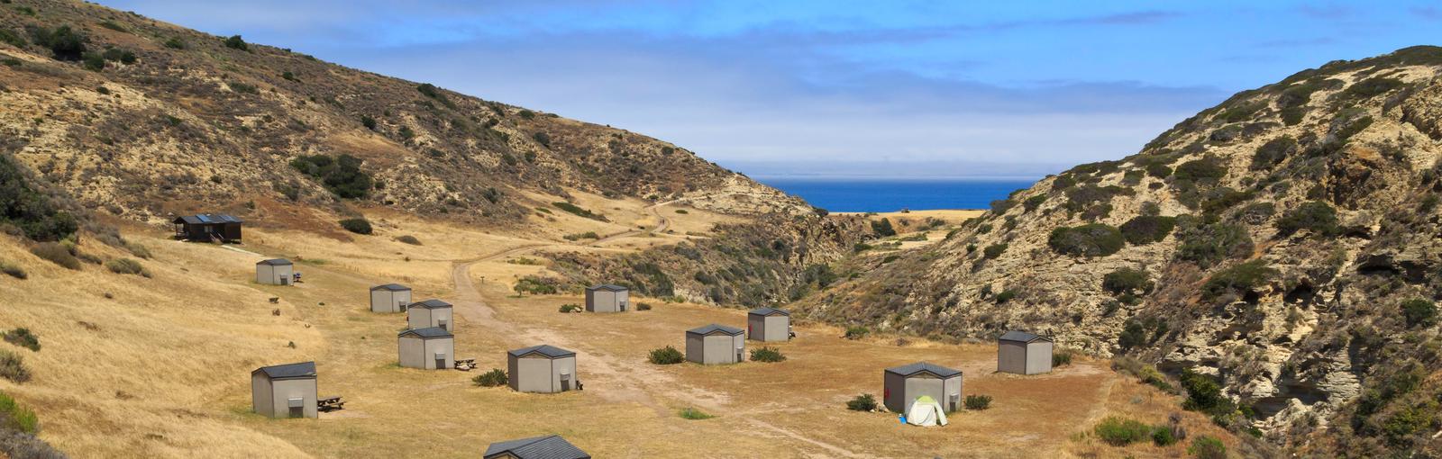 Eight foot tall wind shelters on a dry, grassy terrace overlooking the oceanSanta Rosa campground