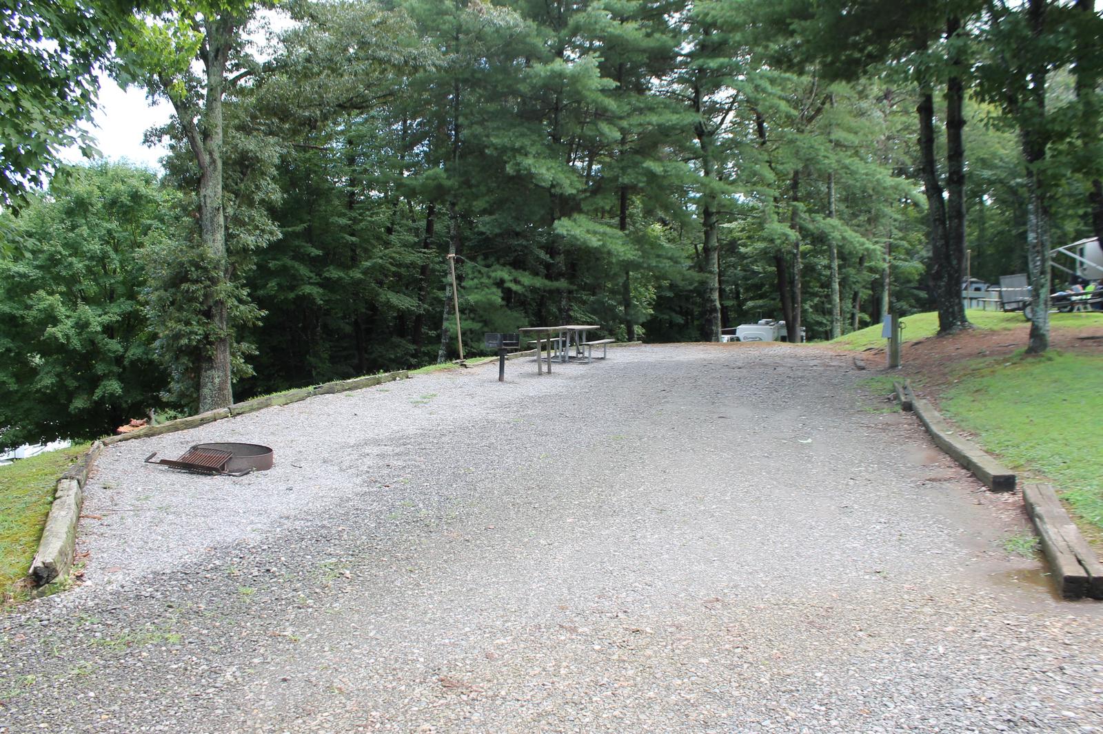 Long gravel pull in site with table, fire pit, grill 