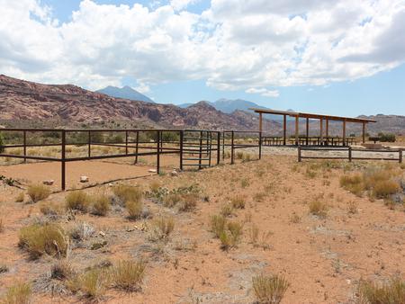 Ken's Lake Group Site A shade shelter, metal fence horse corral, and parking area with the La Sal Mountains in the distance.