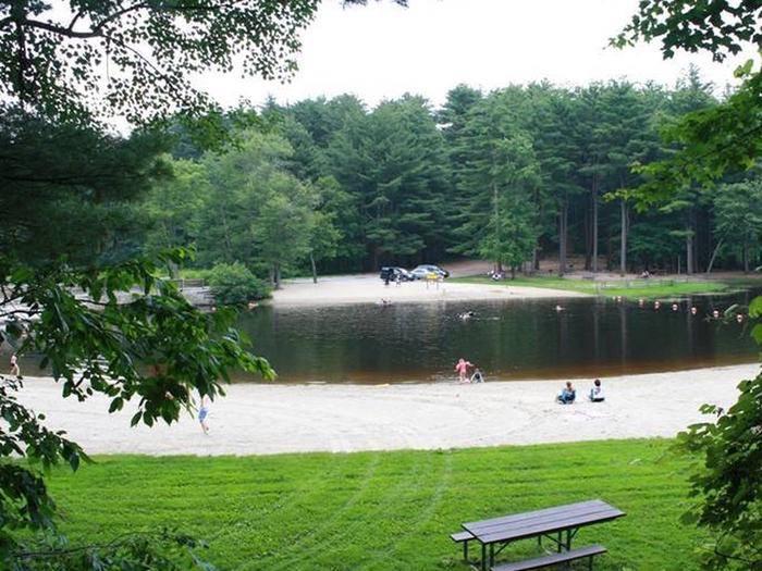 View looking over both sandy swim beaches with green lawns, parking lot and picnic tables in background.Peaceful swim and picnic grove areas with ample parking and grills provided.  Pack your picnic and enjoy your park.