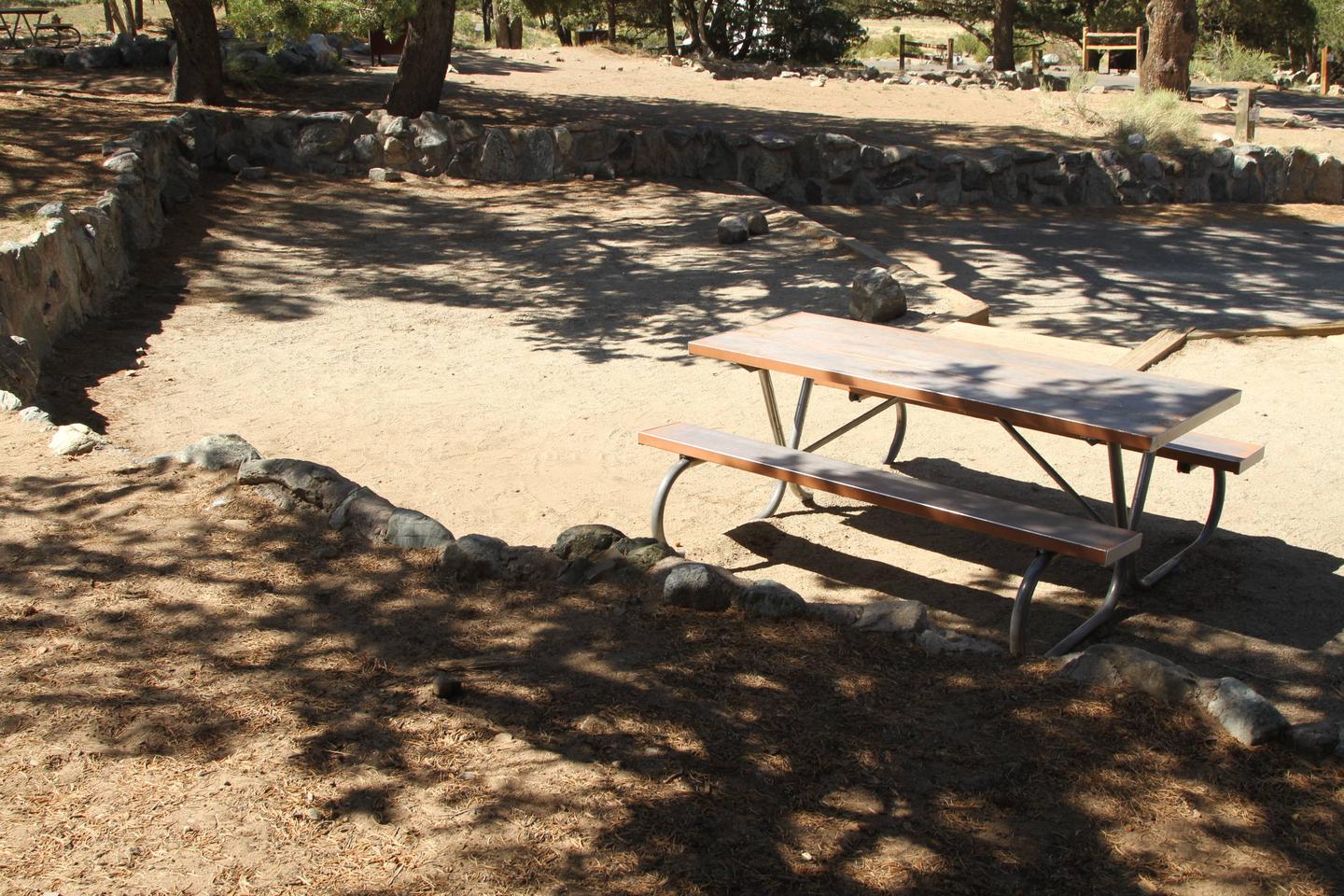 Back view of Site #25 tent pad and picnic table. Tent site area has low rock retainer walls on three sides.Site #25, Pinon Flats Campground