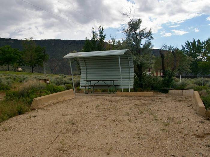 Picnic table with a shelter covering one side and over head and parking in the front.Antelope Campground