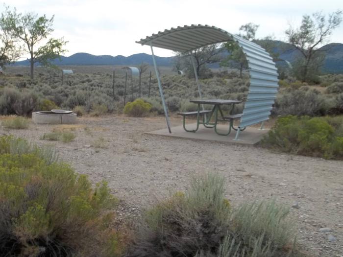 Picnic table with shelter and a fire pit off to the side of it.Antelope Flat Campground: Site 2