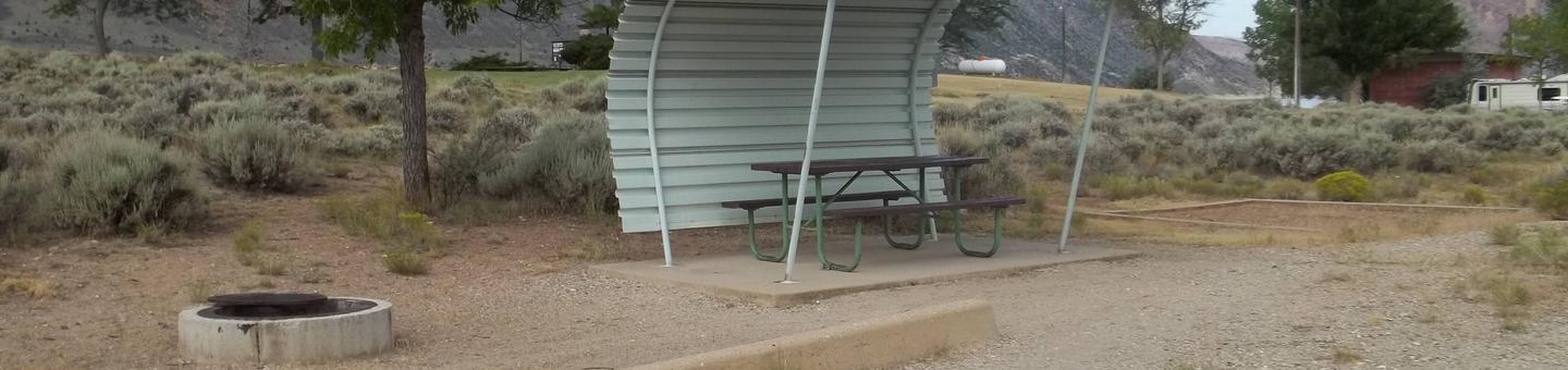 Picnic table with shelter on one side and overhead and a firepit located to the side of the picnic area.Antelope Flat Campground: Site 3