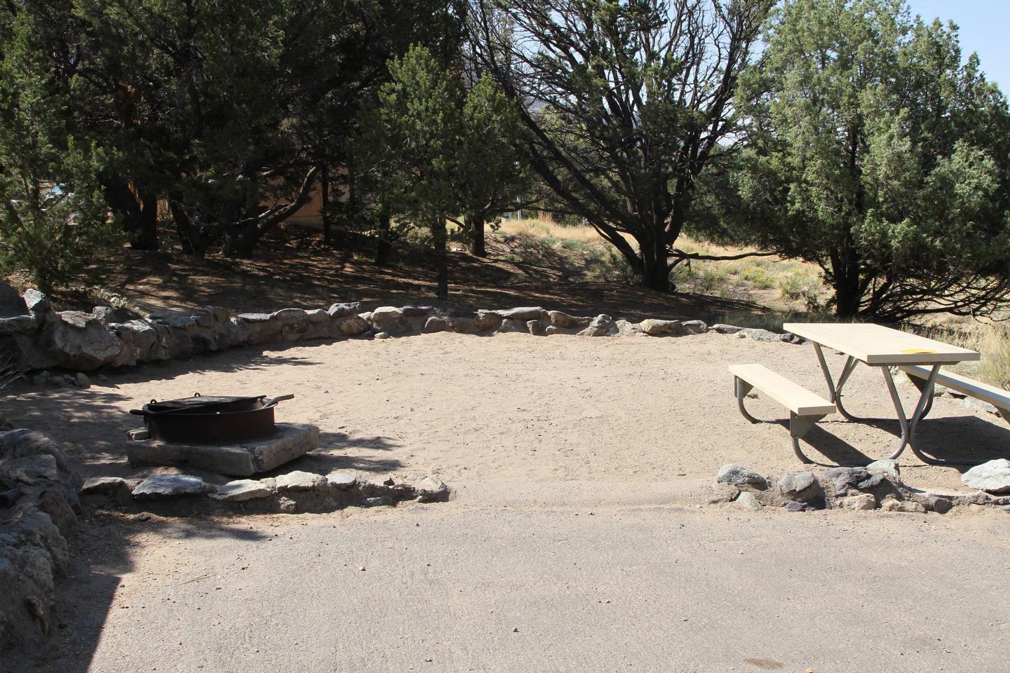 Close up view of Site #65 tent pad, with fire ring and picnic table. Tent pad is bordered by a low rock wall.Site #65, Pinon Flats Campground