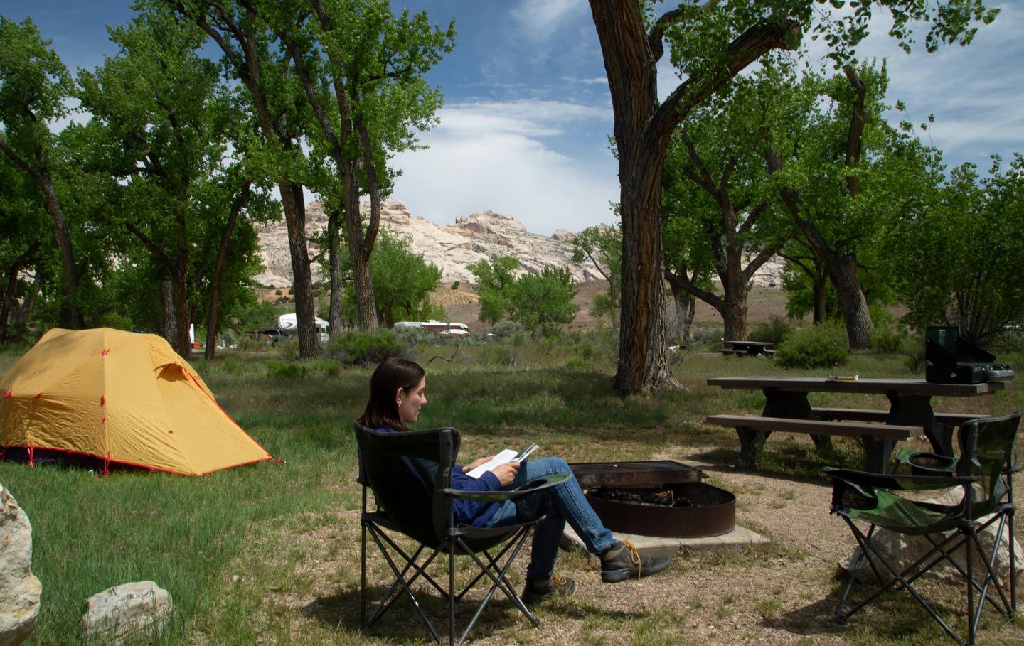 Camper in relaxing in camp chair in campsite. 