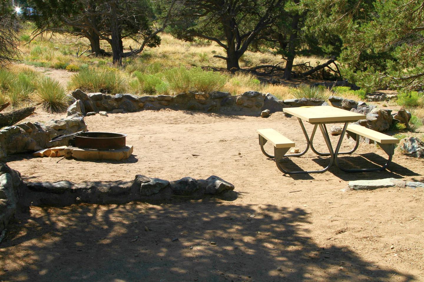 Closer view of Site #70 tent pad with fire ring and picnic table. Tent pad is bordered by a low rock wall.Site #70, Pinon Flats Campground