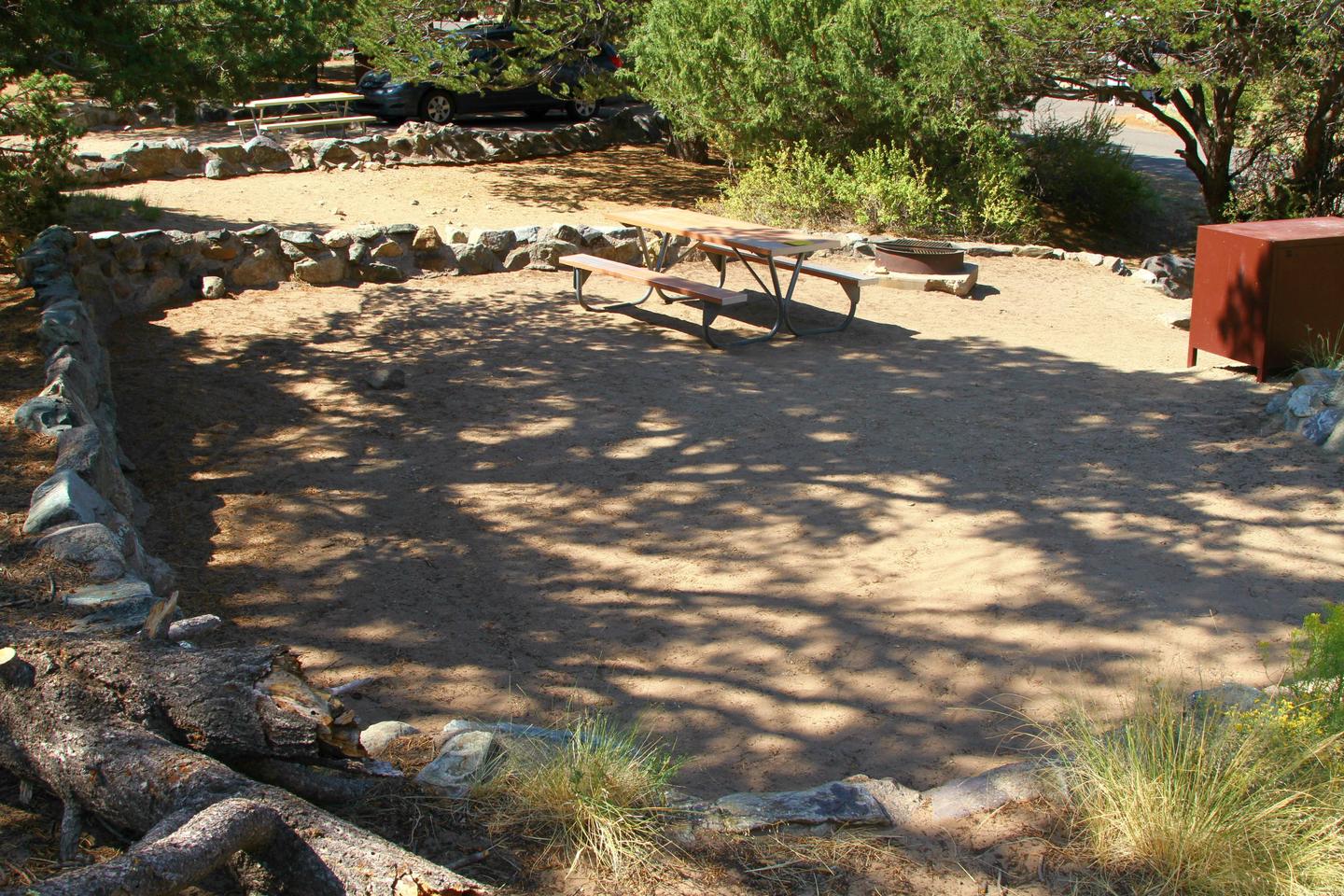 Back view of Site #72 tent pad, with bear box, picnic table and fire ring. Tent pad is bordered by a low rock wall.Site #72, Pinon Flats Campground