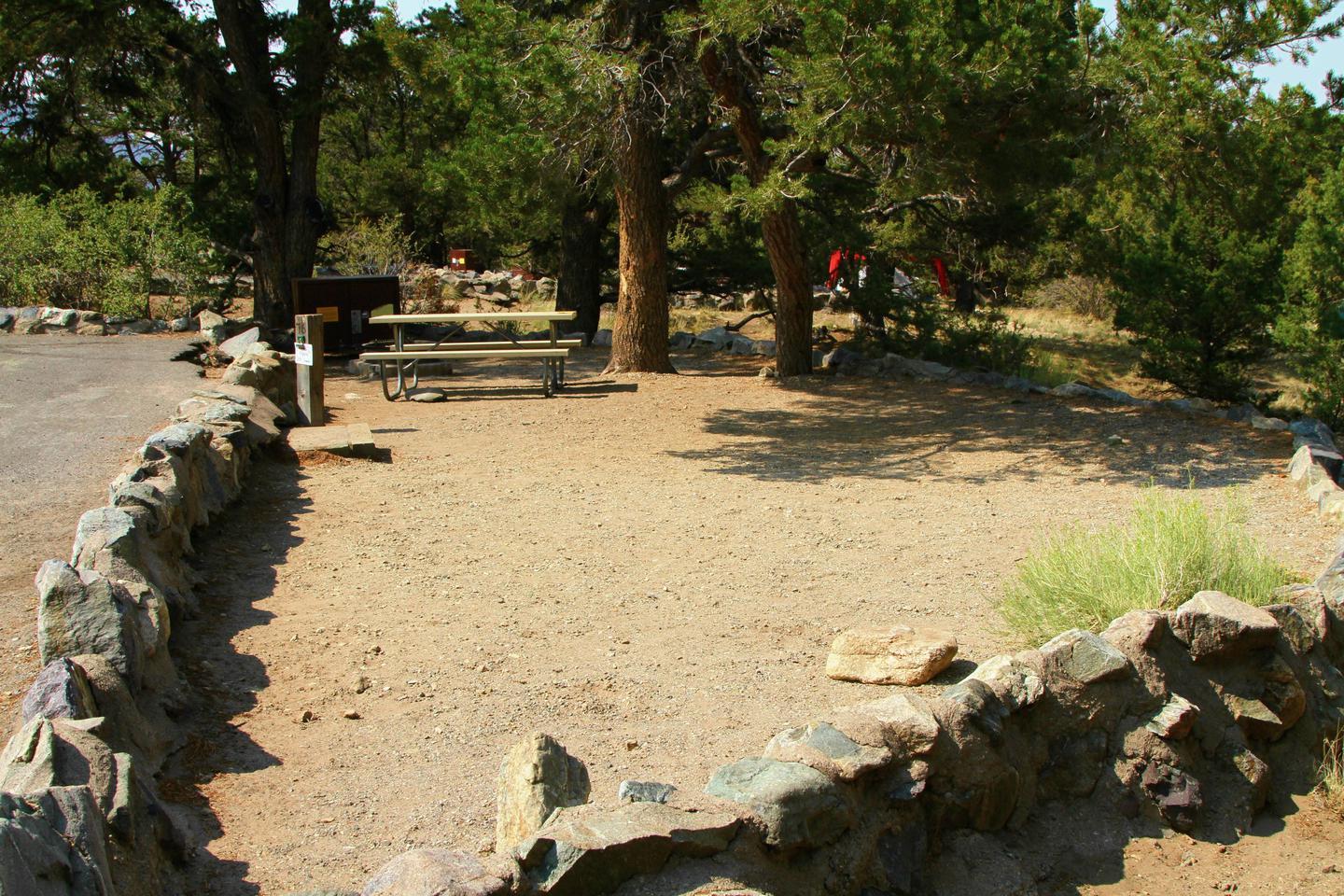 Site view of Site #76 tent pad, showing stairs down from parking area, picnic table, fire ring, and bear box. Tent pad is bordered by a low rock wall.Site #76, Pinon Flats Campground
