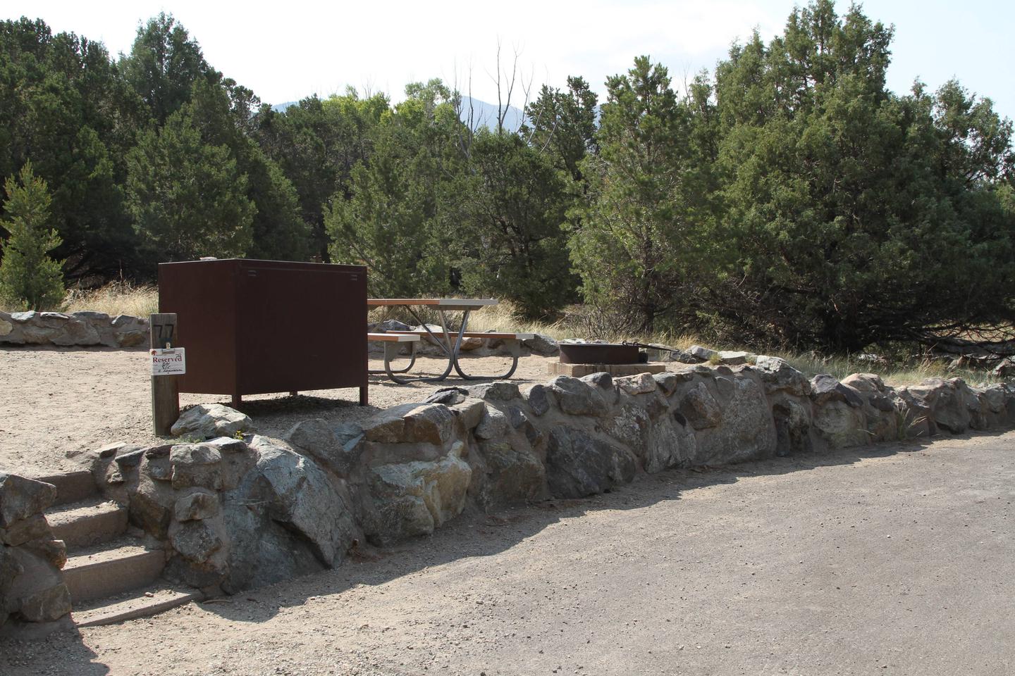 Closer view of Site #77 tent pad from parking area, with stairs going up into site, bear box, picnic table, and fire ring.Site #77, Pinon Flats Campground
