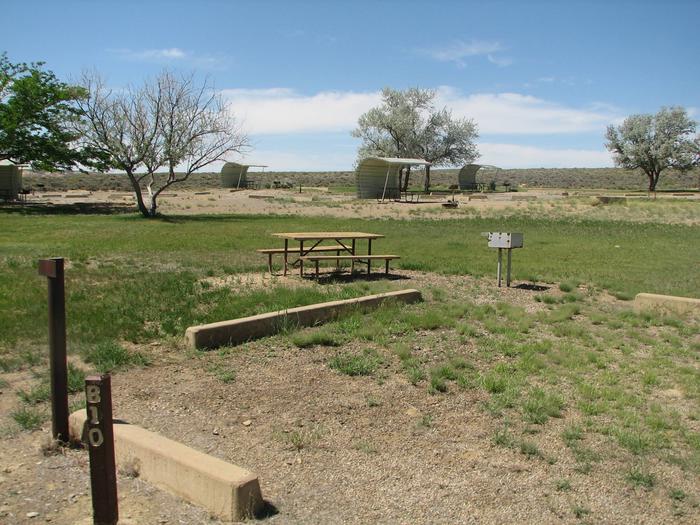 Picnic table and grill in a semi grassy area. There are a few other campgsites in the background.Buckboard Crossing Campground: Loop B, Site 10