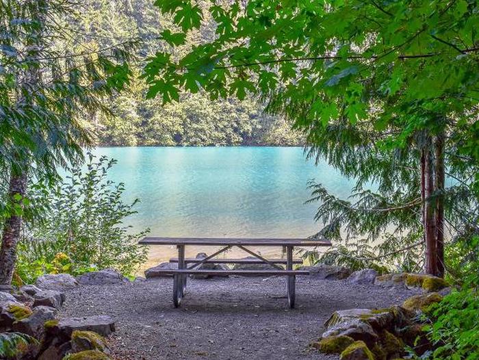 Picnic table with a view of Diablo Lake in a Colonial Creek campsite.View of Diablo Lake from a lakeside campsite at Colonial Creek South Campground.