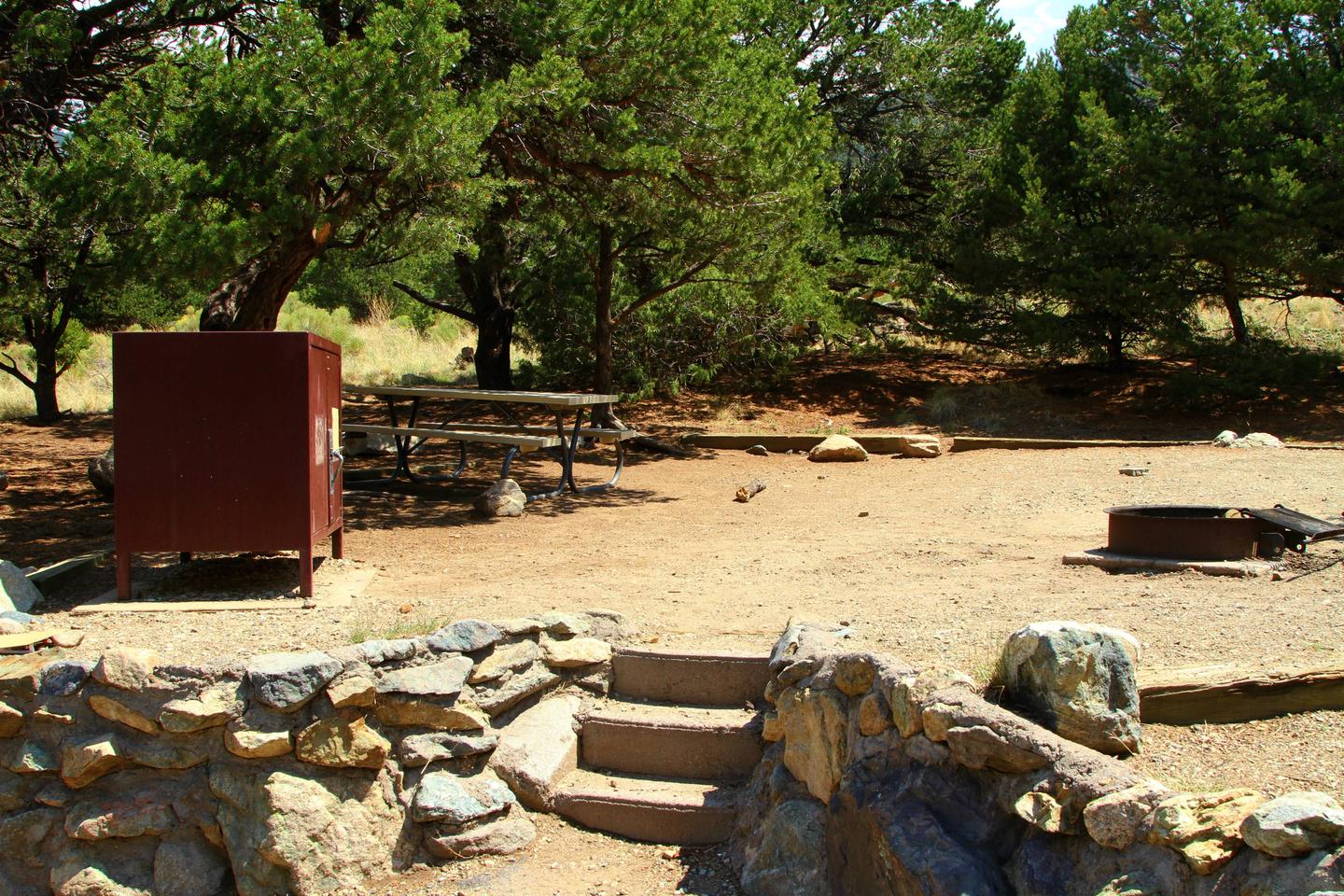 Closeup view of Site #45 designated tent pad, bear box, picnic table, and fire ring. Stairs up from the parallel parking area can be seen in the front.Site #45, Pinon Flats Campground