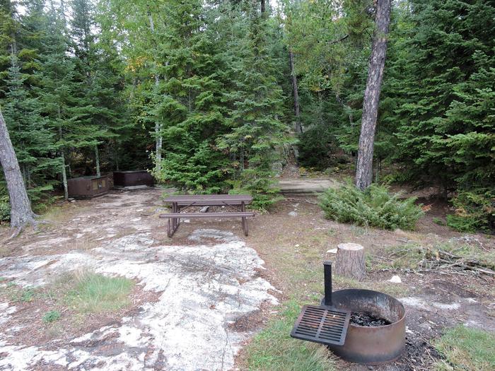 R54 - Beaver Lodge, view into the campsite with a fire ring and picnic table in the foreground and a tent pad and bear boxes in the background.View of campsite