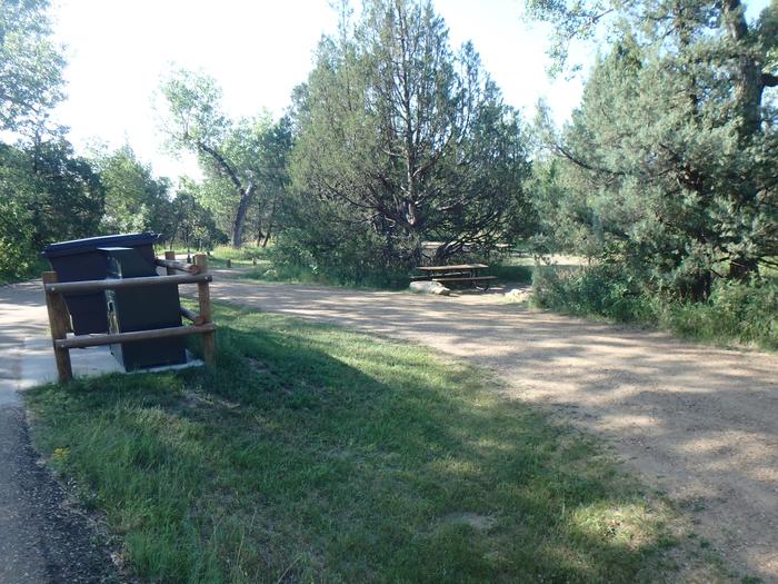Site 27 has dumpsters adjacent to the site.  The picnic table and grill are located on the right side of the site. Site 27. 