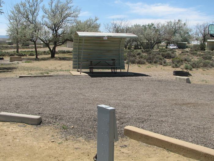 This site has a partially covered picnic table on a slab of cement and a fire pit nearby that is in the gravel.Buckboard Crossing Campground: Loop A, Site 20