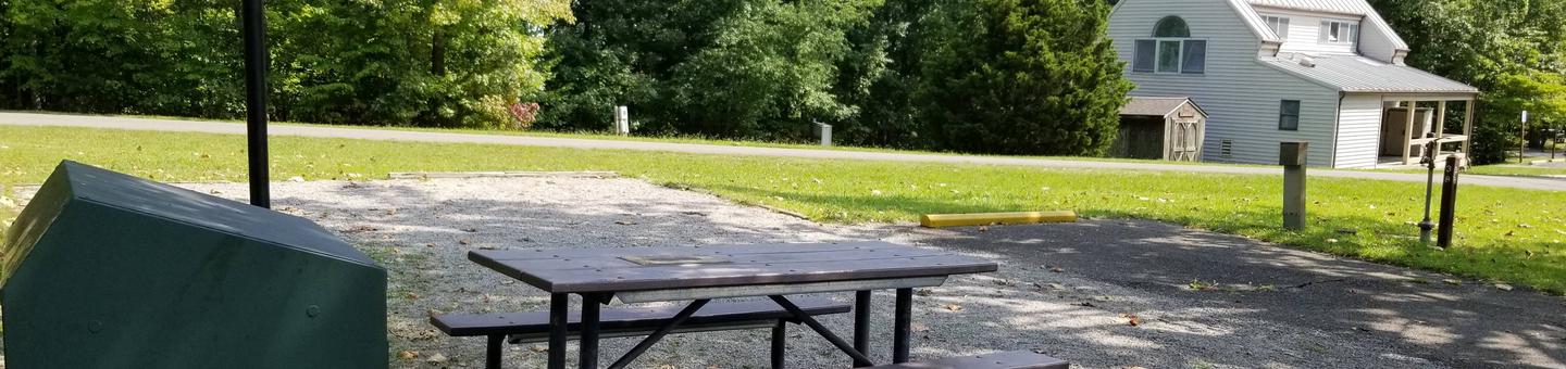 Picnic table sits on gravel tent pad with bathhouse in backgroundBlue Heron Campground