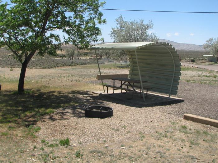 This site has a partially covered picnic table on a slab of cement and a fire pit found in the gravel. Shade can be found in this site.Buckboard Crossing Campground: Loop A, Site 7