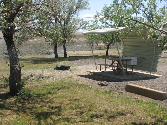This site has a partially covered picnic table on a slab of cement and a fire pit found in the gravel. There area couple of shade trees in this site.Buckboard Crossing Campground: Loop A, Site 9