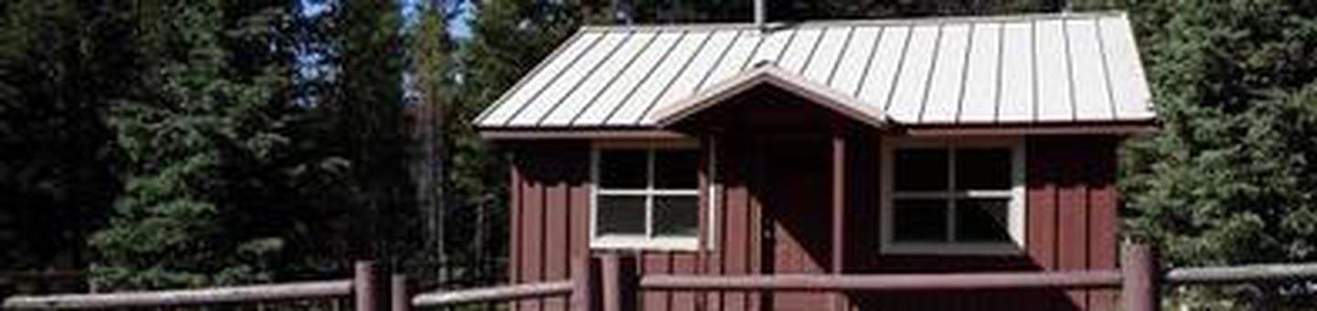 Cabin with red siding in front of conifer forestShort Creek Guard Station